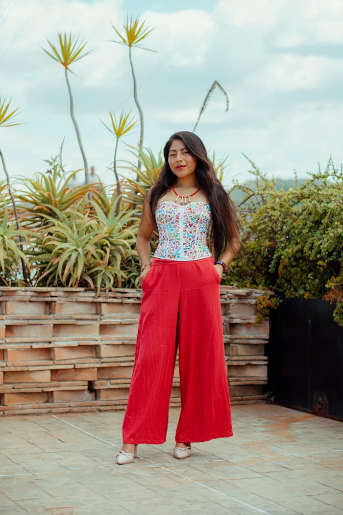 Young woman in vibrant Mexican clothing posing outdoors in Oaxaca, showcasing colorful and traditional fashion.
